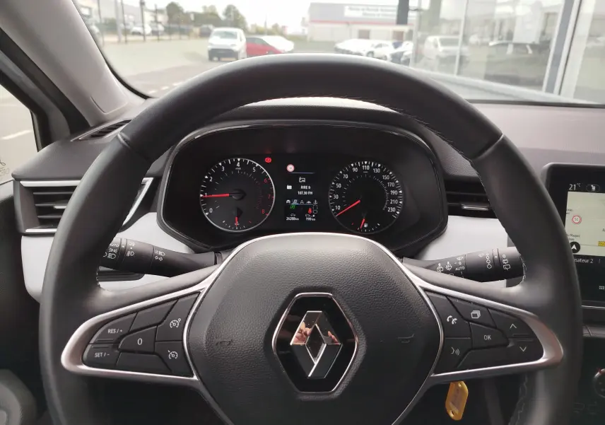 Vue intérieure centrée sur le volant noir de la Renault Clio 2023 avec tableau de bord numérique et commandes intégrées.