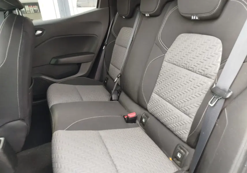 Vue intérieure des sièges arrière gris clair et noir de la Renault Clio 2023, avec ceinture de sécurité et appuie-têtes visibles.