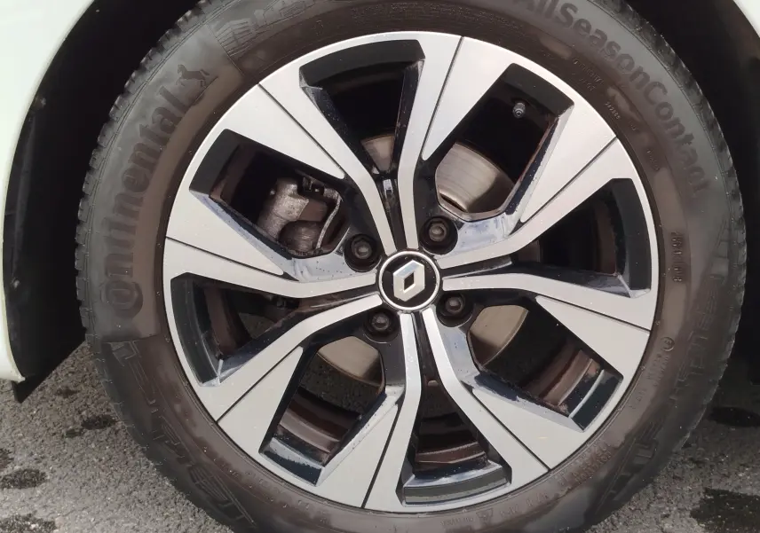Gros plan sur la jante alliage bicolore noir et argent avec logo Renault, montée sur pneu Continental AllSeason.