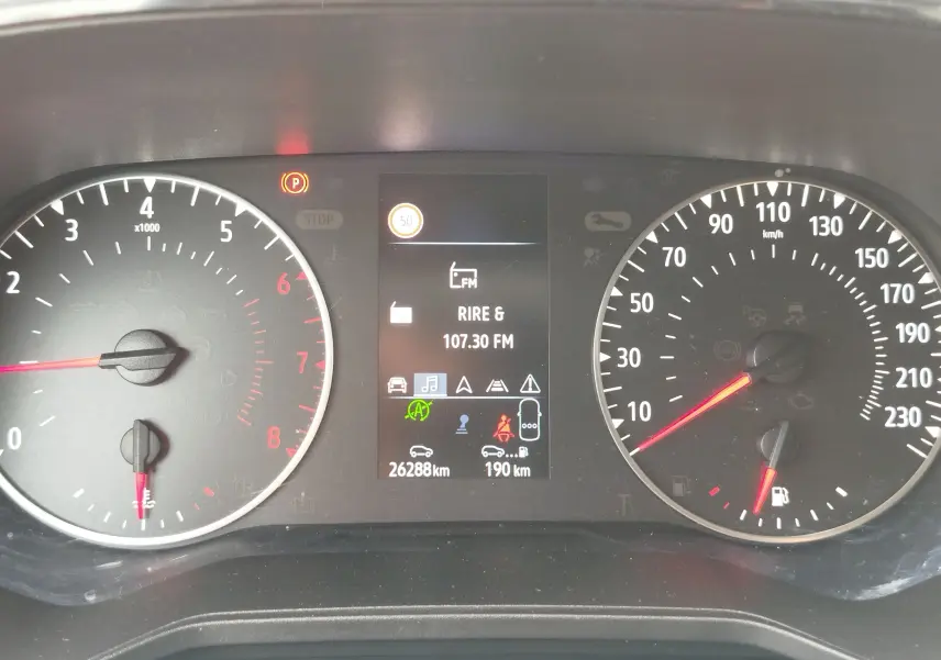 Tableau de bord de Renault Clio 2023, affichage central numérique avec compte-tours et vitesse en km/h, témoin parking allumé.