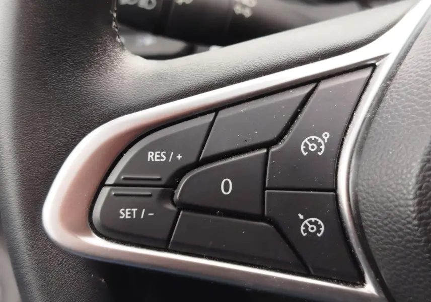 Gros plan sur les commandes de régulateur de vitesse au volant noir de la Renault Clio 2023.