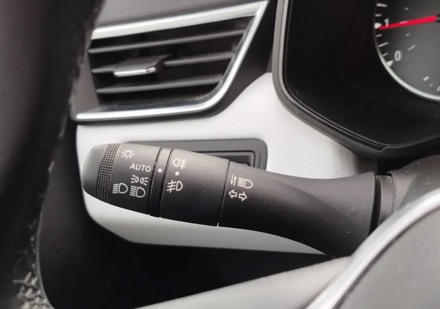 Gros plan sur la commande des feux et clignotants dans l’habitacle blanc gris d’une Renault Clio 1.0 SCe 65ch Evolution 2023.