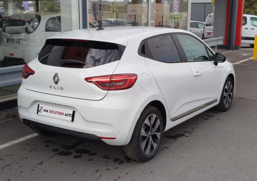Vue 3/4 arrière droite d'une Renault Clio blanche Glacier 2023 avec jantes alliage et vitres teintées.
