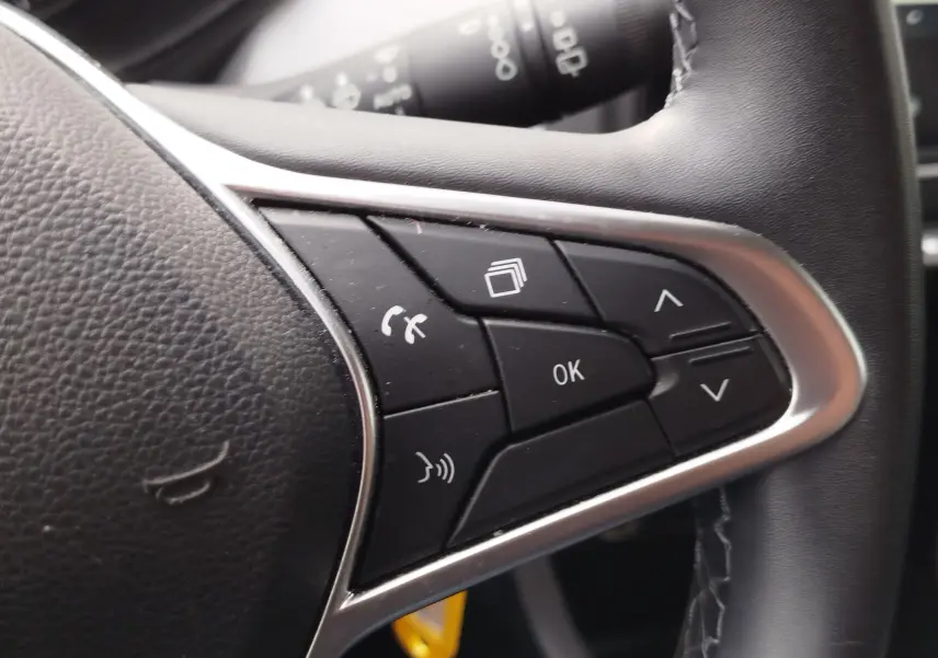 Gros plan sur les commandes multifonctions à droite du volant noir de la Renault Clio 1.0 SCe 65ch Evolution 2023.