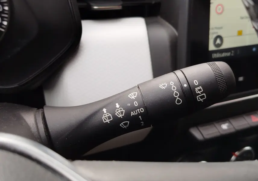 Gros plan sur la commande des essuie-glaces dans l’habitacle blanc et noir d’une Renault Clio 2023.