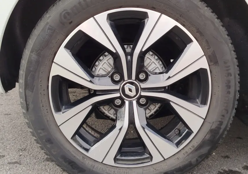 Gros plan sur la jante alliage bicolore noire et argentée de la Renault Clio blanche, avec logo Renault au centre.