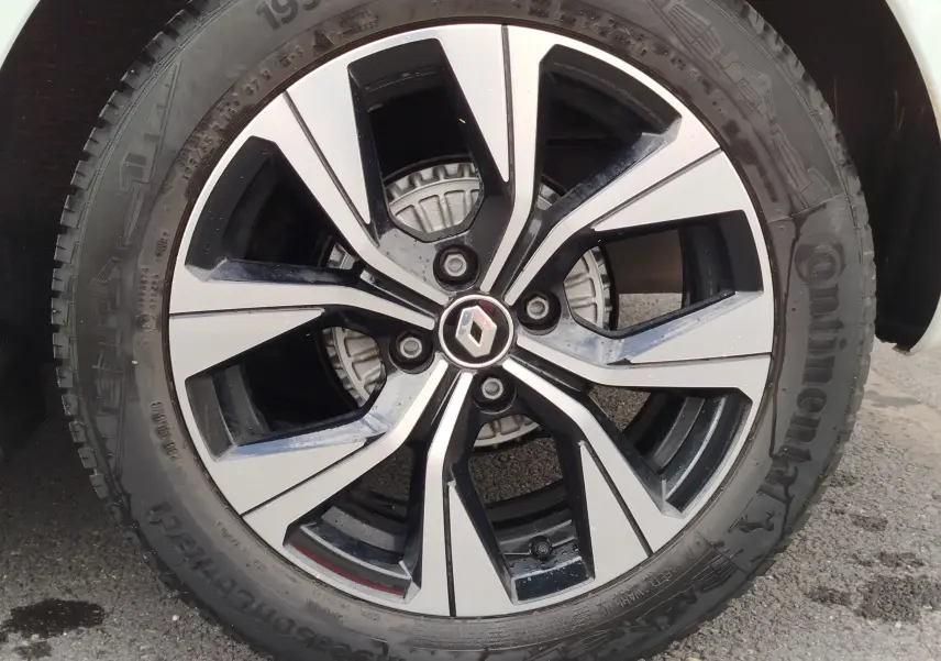 Gros plan sur la jante alliage bicolore noire et argentée d'une Renault Clio Blanc Glacier, avec logo Renault au centre.