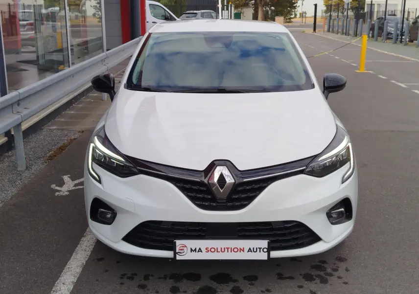 Vue frontale d'une Renault Clio blanche Glacier 2023 avec phares LED allumés et calandre noire brillante.