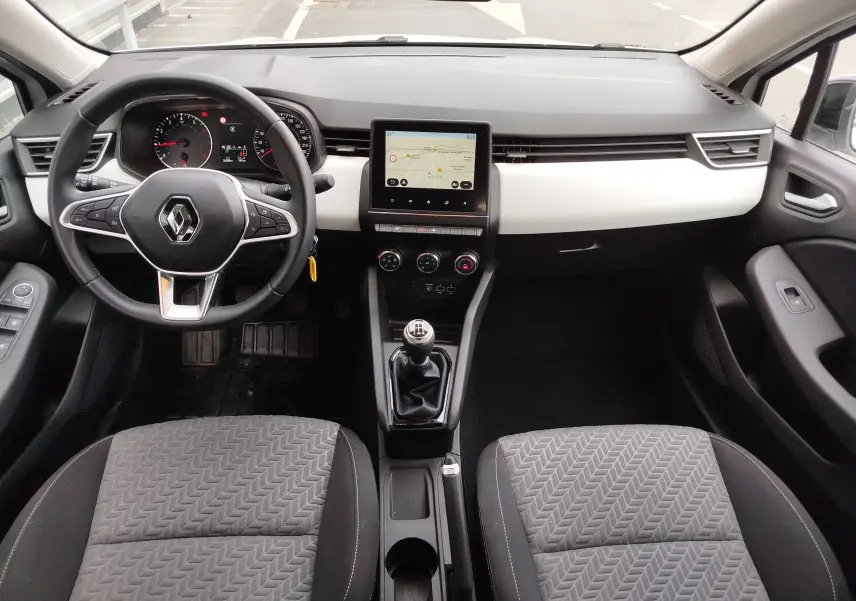 Vue intérieure avant de la Renault Clio 1.0 SCe 65ch Evolution 2023, tableau de bord noir et blanc avec écran tactile central.