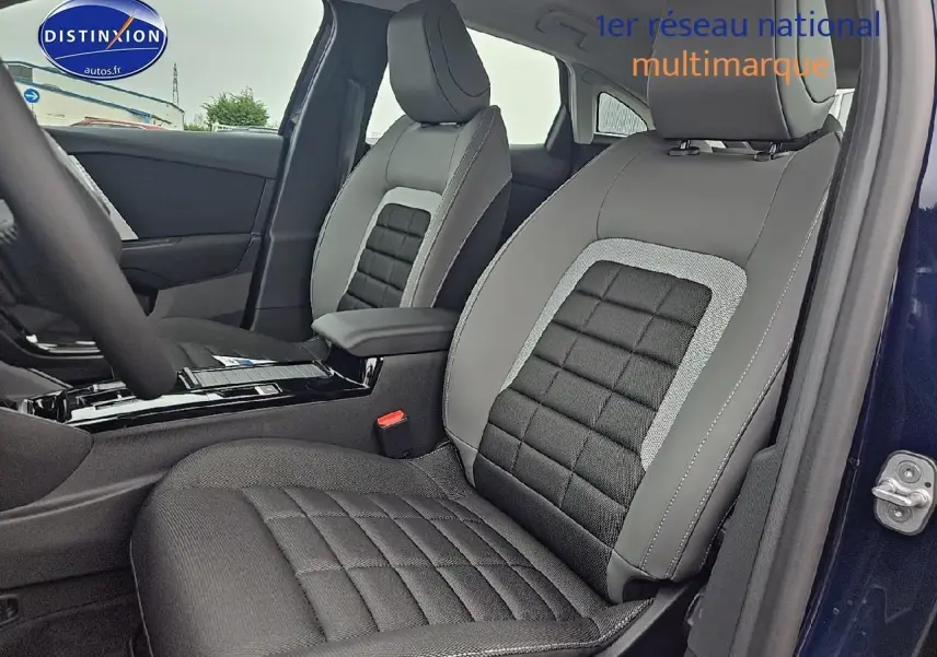 Intérieur côté droit de la Citroën C4 1.2 hybride 136 plus 2025 avec sièges tissu noir et gris et accoudoir central.