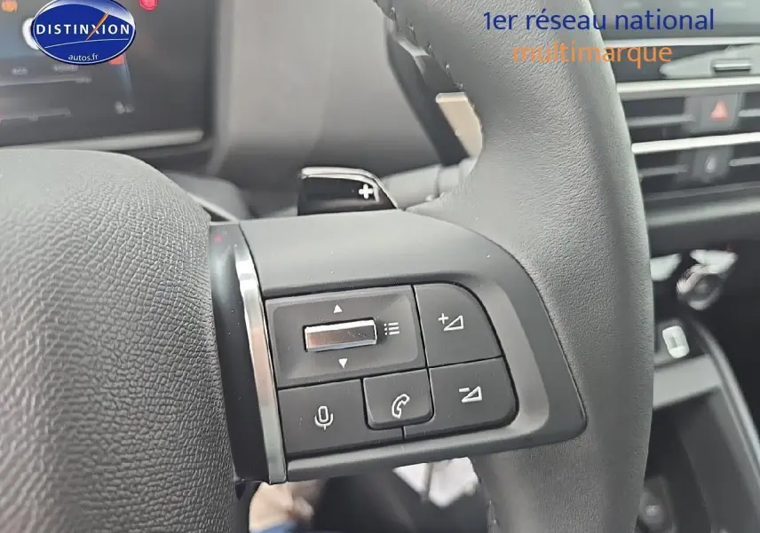 Gros plan sur les commandes audio et téléphone au volant en cuir noir de la Citroën C4 1.2 hybride 136 plus 2025.
