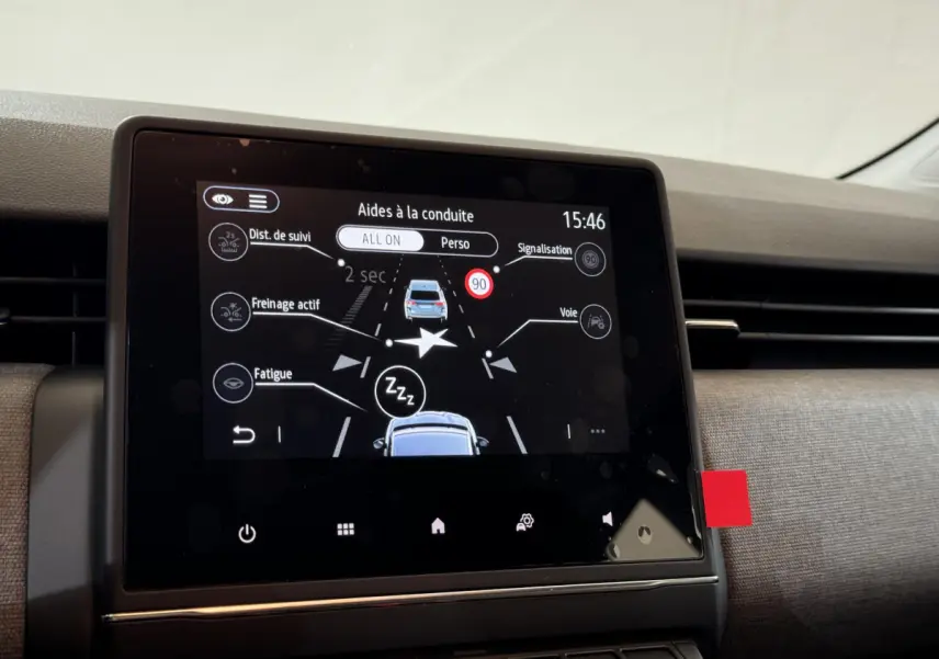 Écran tactile central affichant les aides à la conduite dans une Renault Clio gris clair, vue intérieure frontale.