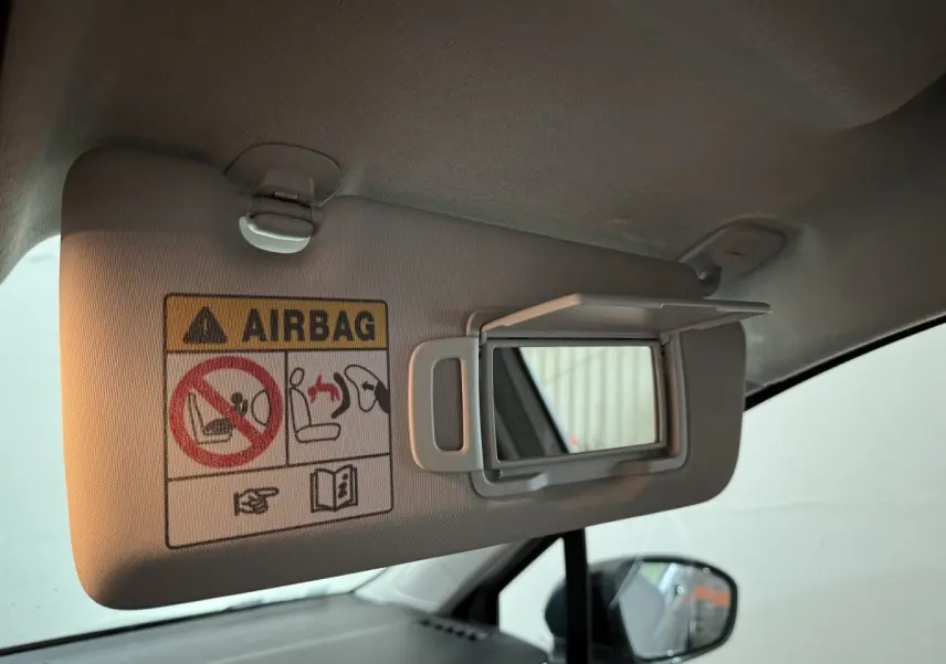 Détail du pare-soleil côté conducteur avec miroir et avertissement airbag dans une Renault Clio gris clair, vue intérieure.