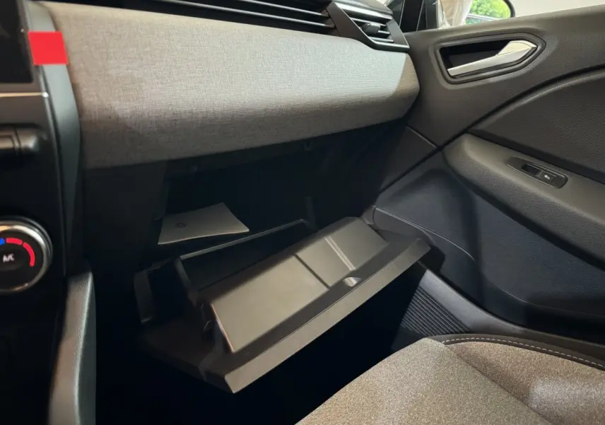 Intérieur de la Renault Clio 2025, vue côté passager sur la boîte à gants ouverte et le tableau de bord gris clair.