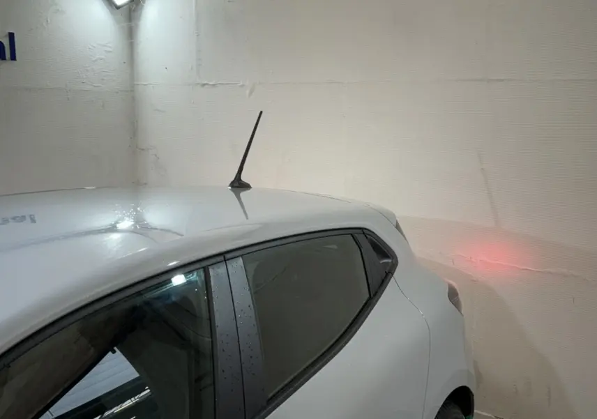 Vue arrière côté gauche d'une Renault Clio gris clair 2025 avec antenne sur le toit et vitre arrière teintée.