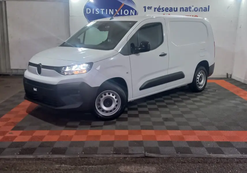 Vue 3/4 avant gauche d’un utilitaire Citroën Berlingo blanc avec phares allumés et jantes acier.