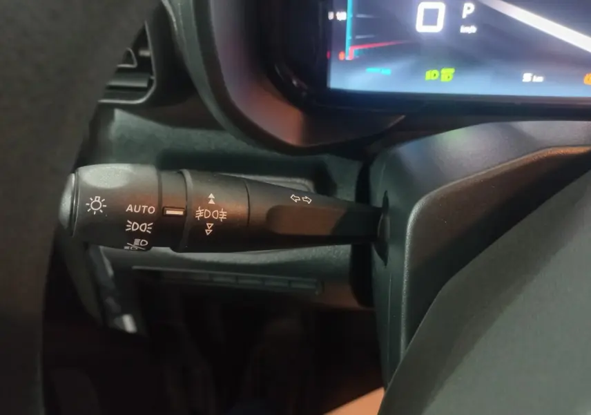 Gros plan sur la commande des feux et clignotants à gauche du volant dans l'habitacle du Citroën Berlingo blanc.