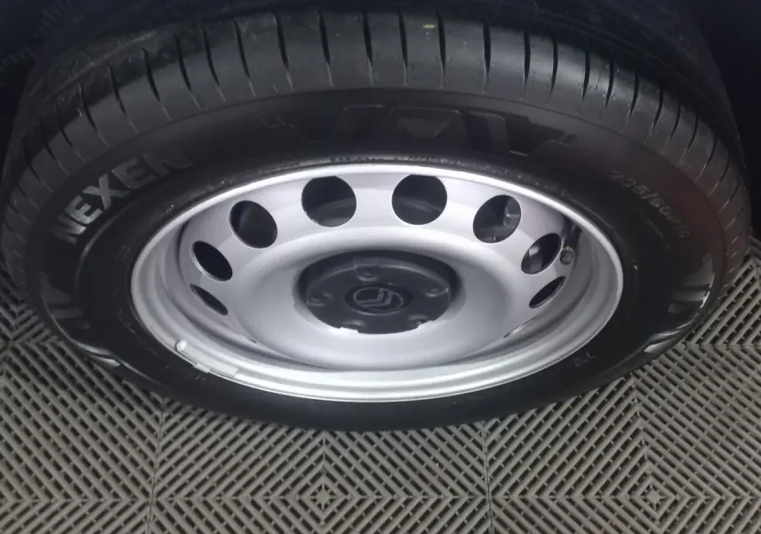 Gros plan sur la roue acier argentée avec pneu Nexen d’un Citroën Berlingo blanc, vue de dessus.