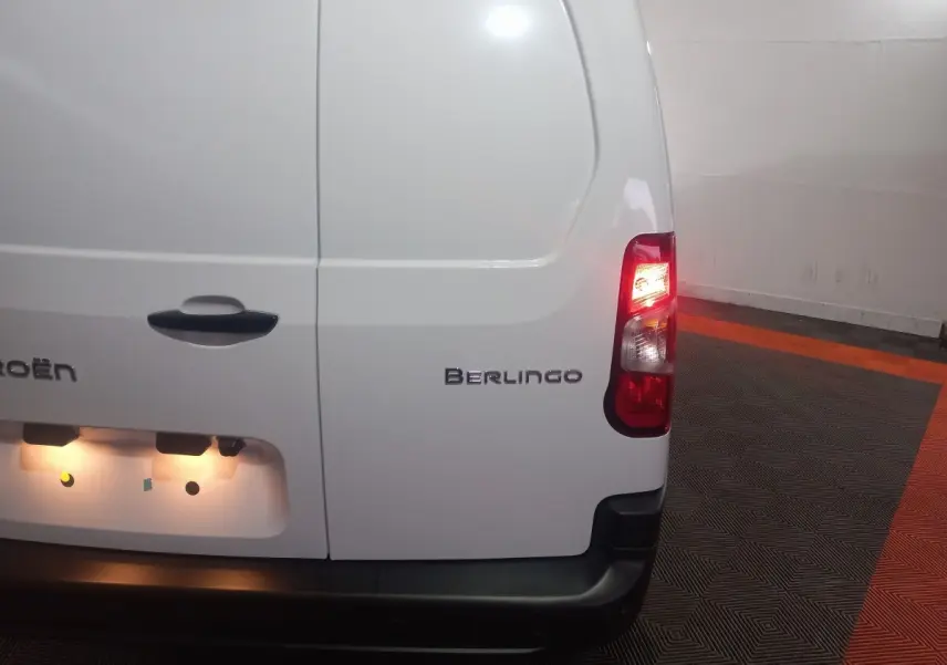 Vue arrière droite d'un Citroën Berlingo blanc avec feu arrière allumé dans un garage.