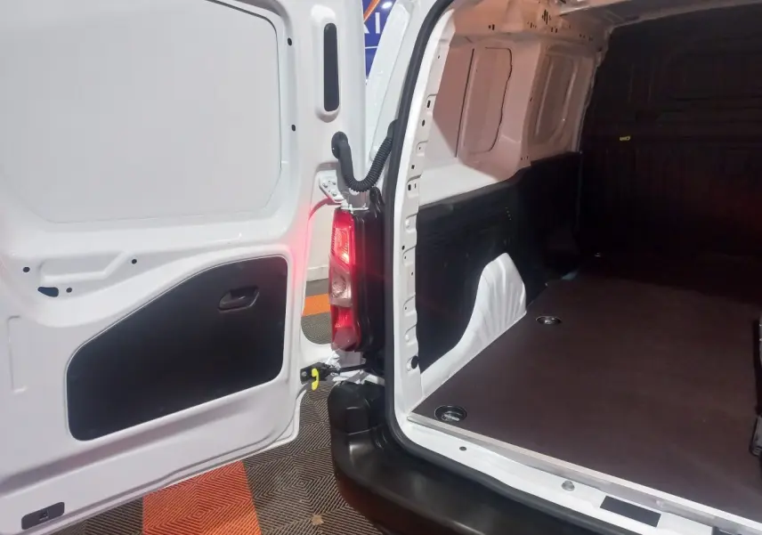 Vue intérieure arrière du Citroën Berlingo XL blanc, montrant la porte ouverte et l'espace de chargement vide.