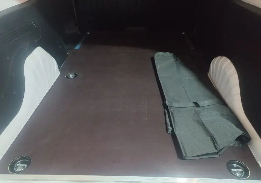 Vue intérieure du coffre du Citroën Berlingo XL blanc 2025, montrant la surface de chargement plane avec un tapis noir partiellement plié.