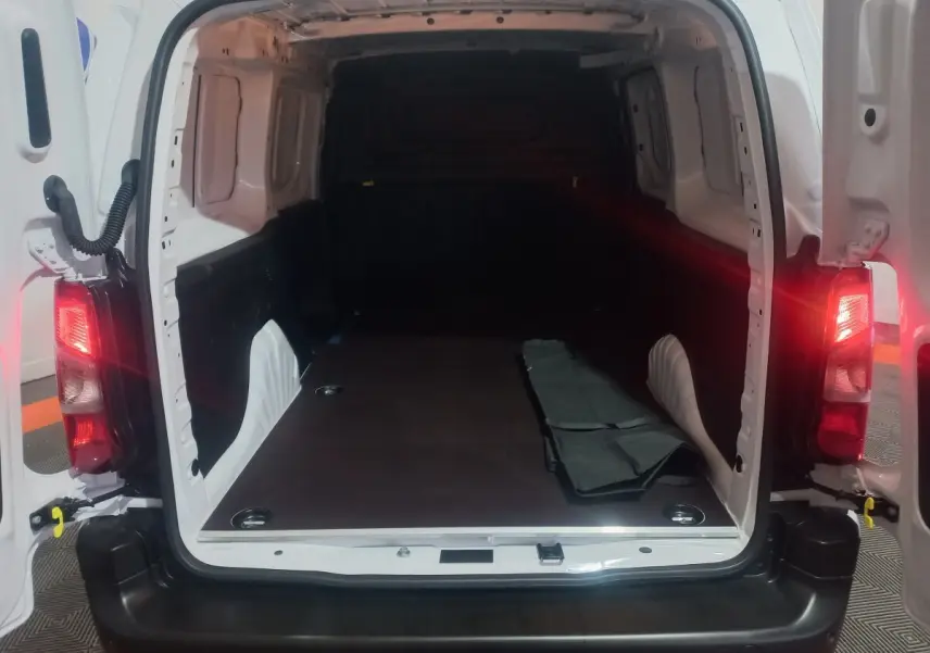 Vue arrière ouverte du Citroën Berlingo XL blanc 2025, montrant l’espace de chargement vide avec plancher plat et tapis partiel.