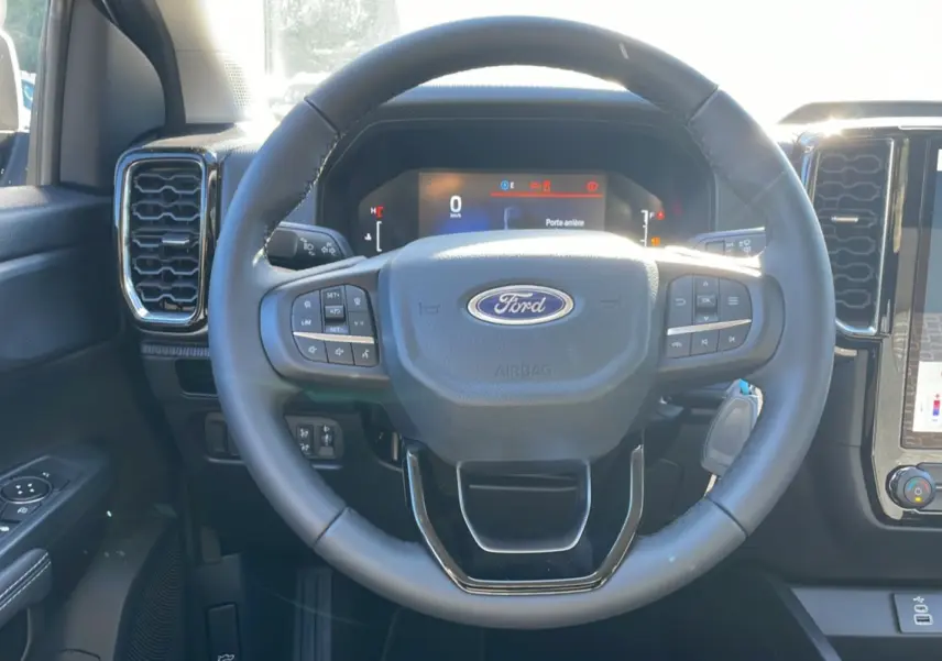 Vue intérieure centrée sur le volant cuir multifonctions du Ford Ranger gris avec tableau de bord numérique.