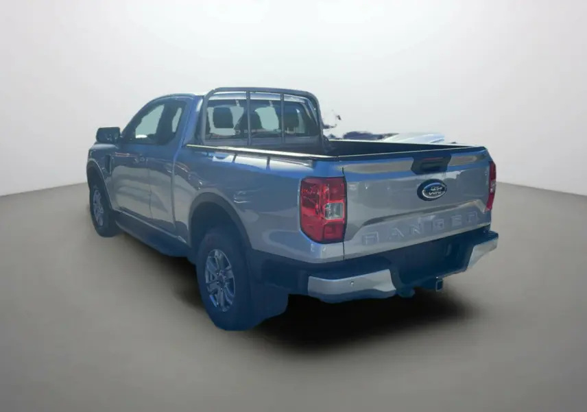 Ford Ranger gris iconic en 3/4 arrière droit, avec benne ouverte et marchepieds latéraux visibles.