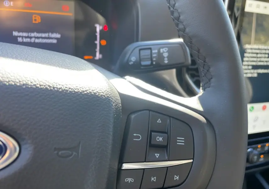 Gros plan sur le volant cuir multifonctions du Ford Ranger gris iconic, tableau de bord et écran tactile en arrière-plan.