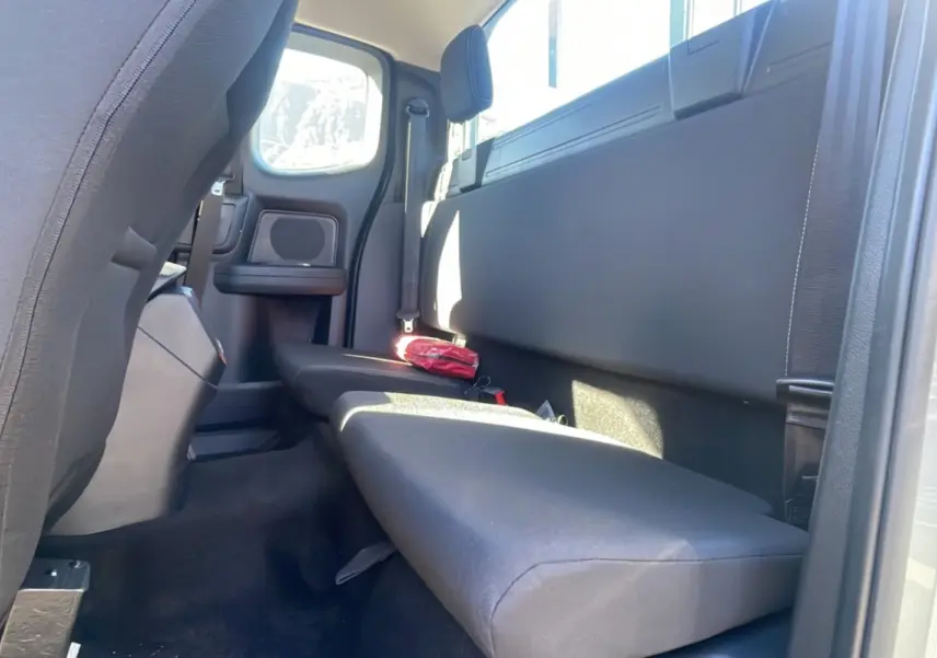 Vue intérieure arrière côté droit du Ford Ranger gris iconic, banquette simple avec trousse de secours rouge posée dessus.