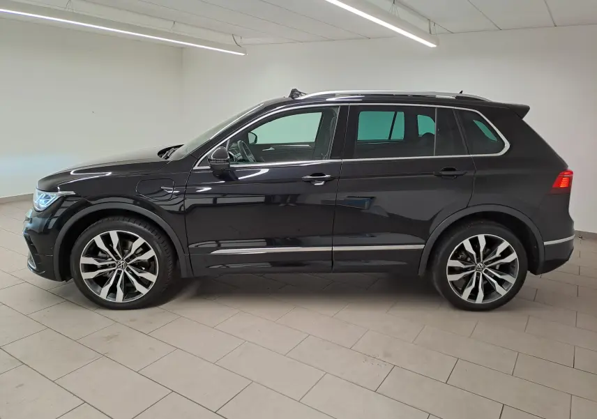 Vue de profil côté gauche d'un Volkswagen Tiguan 1.4 eHybrid noir intense nacré avec jantes 20'' Suzuka et attelage escamotable.