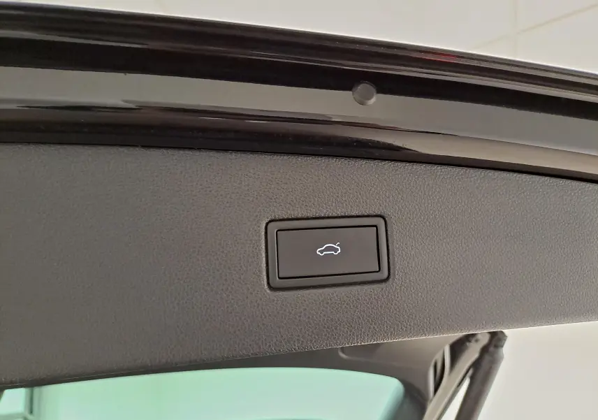 Bouton d'ouverture électrique du hayon sur la partie intérieure du coffre d'un Volkswagen Tiguan noir intense nacré.