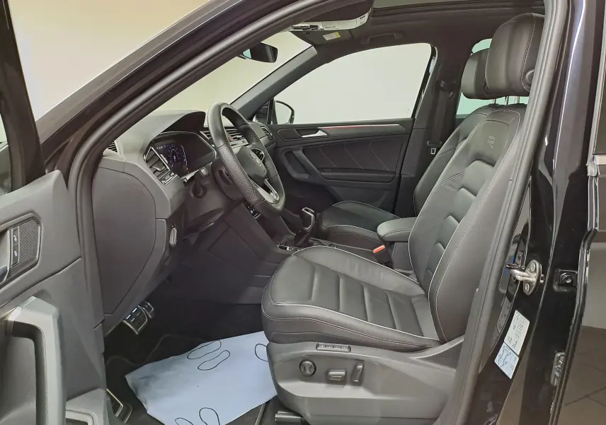 Vue intérieure côté conducteur du Volkswagen Tiguan 1.4 eHybrid 2023 noir intense nacré avec sièges cuir et tableau de bord moderne.