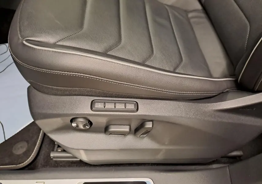 Gros plan sur le siège conducteur noir cuir du Volkswagen Tiguan 1.4 eHybrid 2023 avec réglages électriques et mémoire.