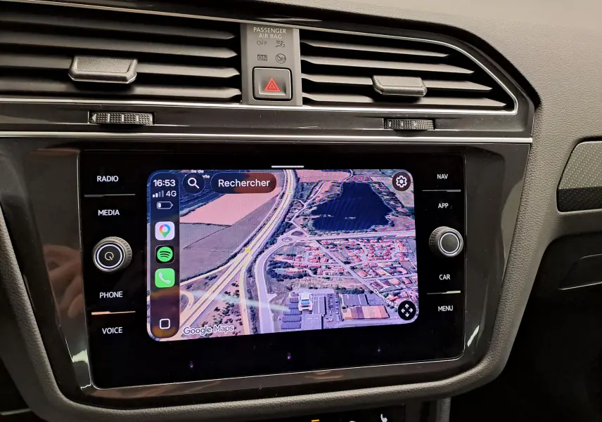 Écran tactile du système multimédia du Volkswagen Tiguan 2023 affichant une carte GPS, entouré de commandes noires.