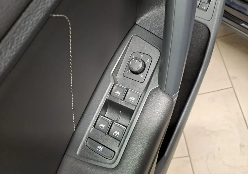 Gros plan sur la commande des vitres et rétroviseurs côté conducteur du Volkswagen Tiguan noir intense nacré 2023.