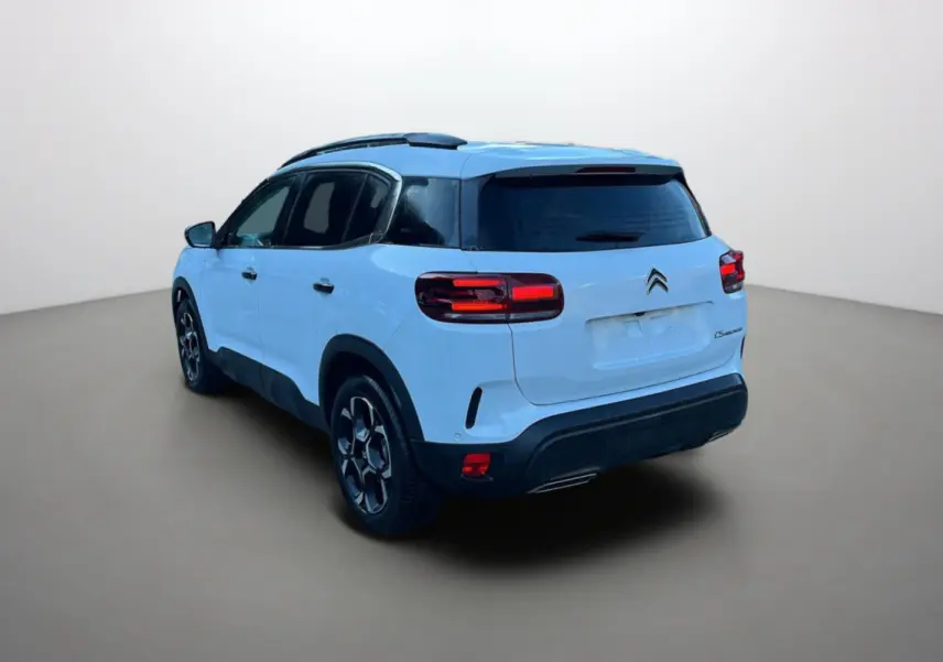 Vue 3/4 arrière gauche d'un Citroën C5 Aircross blanc okénite avec vitres surteintées et jantes alu 18 pouces.