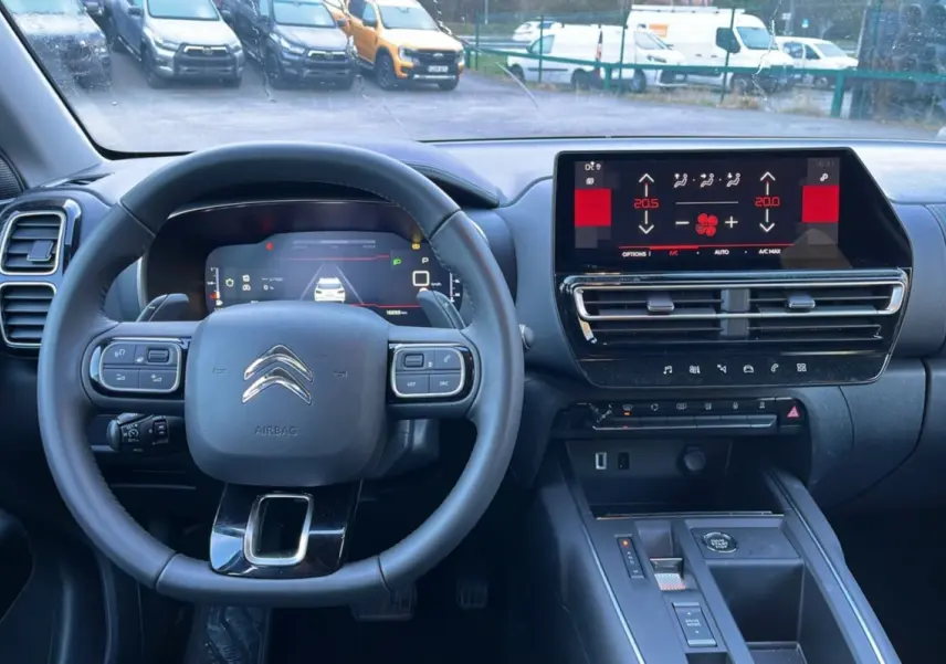 Vue intérieure centrée sur le volant cuir multifonctions et l’écran tactile du tableau de bord du Citroën C5 Aircross Hybrid.