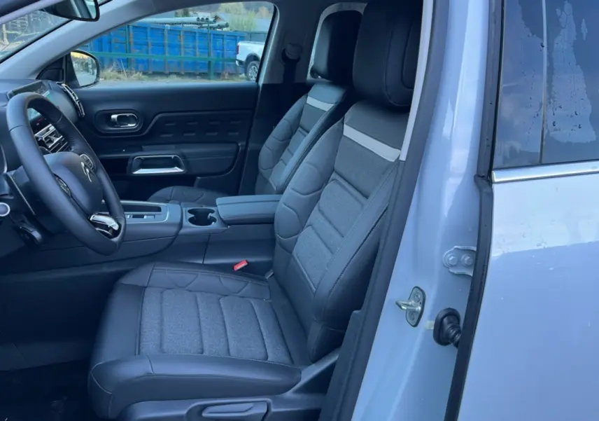 Vue intérieure côté conducteur du Citroën C5 Aircross blanc okénite, montrant les sièges advanced comfort et le volant cuir multifonctions.