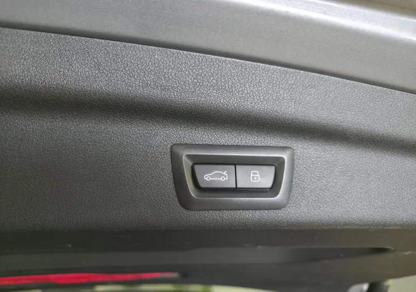 Gros plan sur les boutons d'ouverture et de verrouillage du hayon intérieur d'une BMW Série 2 gris métallisé.
