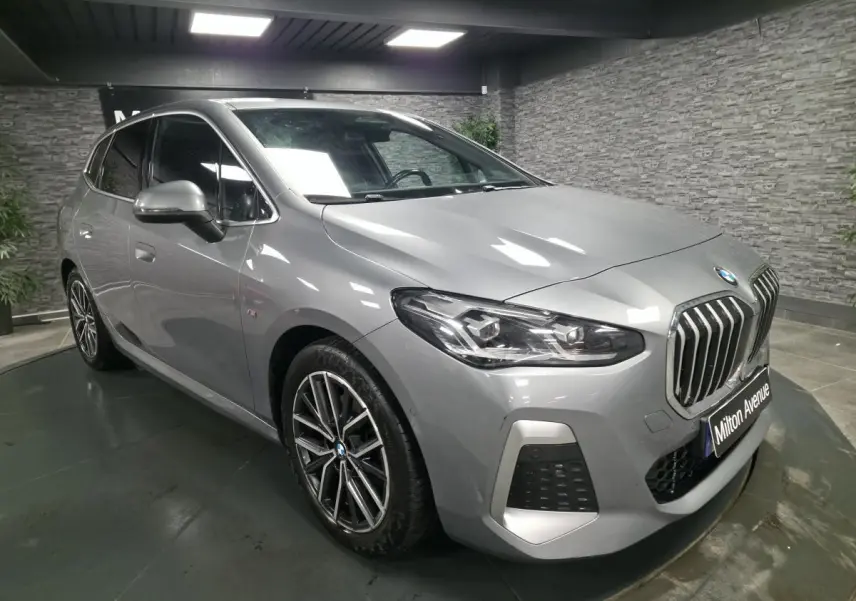 BMW Série 2 218i Active Tourer gris métallisé vue 3/4 avant avec calandre verticale et jantes 18 pouces M bicolores.