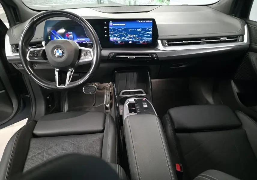 Vue intérieure avant de la BMW Série 2 218i Active Tourer 2023, tableau de bord numérique et volant cuir M noir.