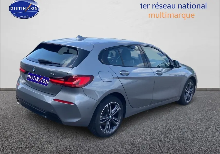 Vue 3/4 arrière droite d'une BMW Série 1 gris foncé avec jantes alliage et feux LED distinctifs.