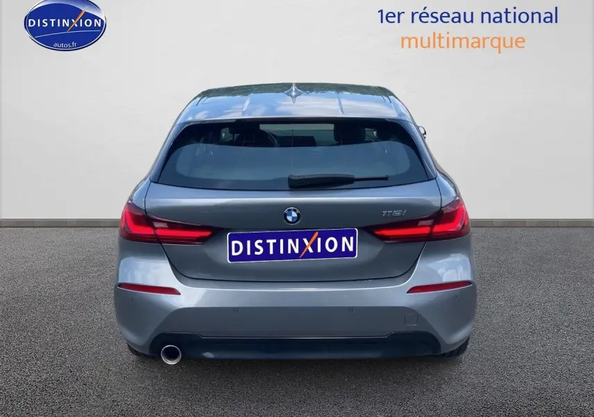 Vue arrière d'une BMW Série 1 118i gris foncé avec feux LED et échappement visible côté gauche.