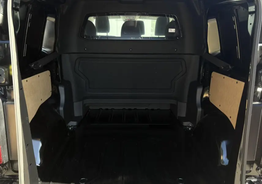 Vue intérieure arrière du Citroën Jumpy noir Perla, montrant l'espace de chargement vide et les panneaux latéraux en bois.
