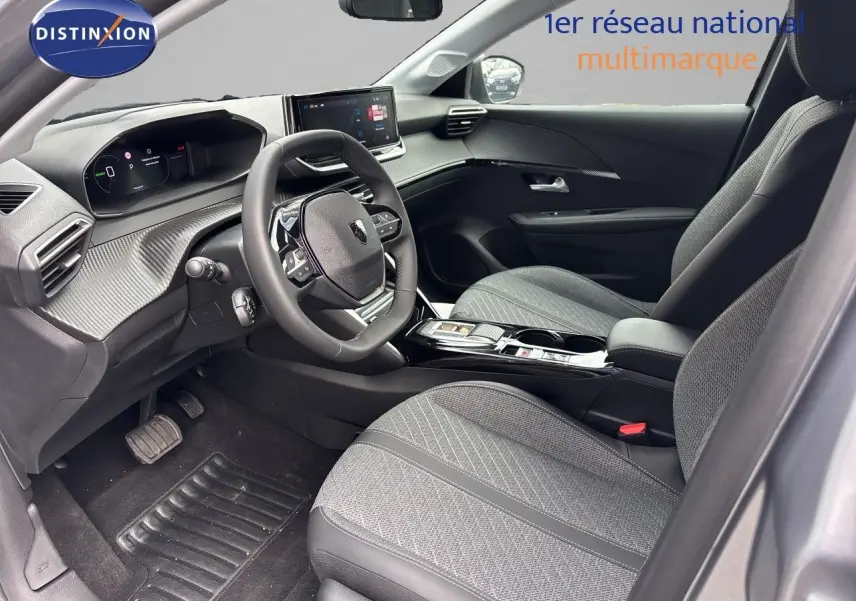 Vue intérieure côté conducteur de la Peugeot 208 électrique 2026 avec sièges gris et tableau de bord moderne.