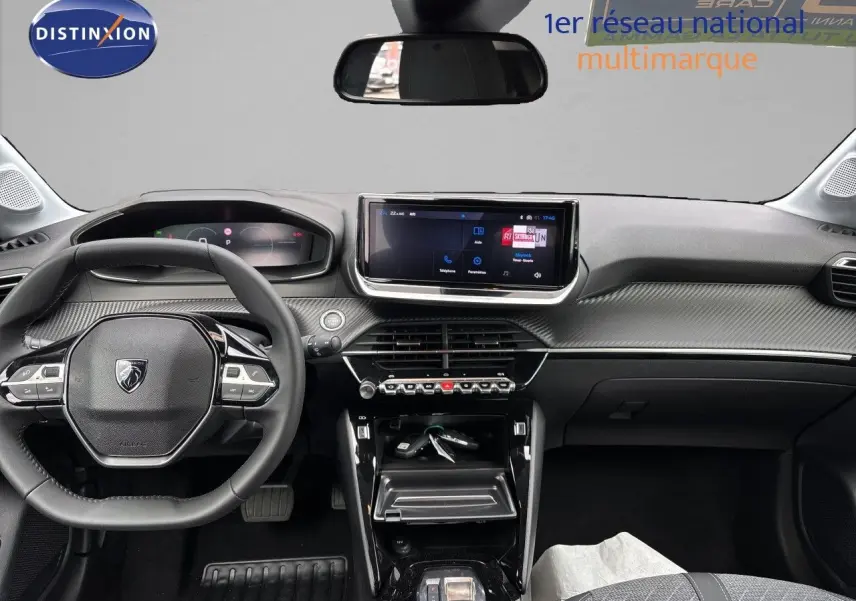 Vue intérieure avant de la Peugeot 208 électrique gris Artense, tableau de bord avec écran tactile et volant multifonction.
