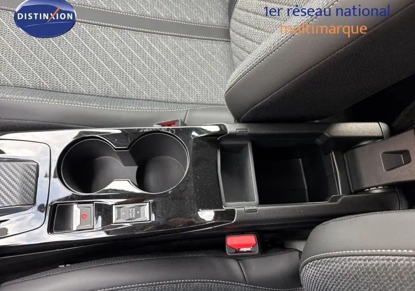 Vue rapprochée de la console centrale noire brillante avec porte-gobelets et accoudoir, sièges tissu gris et cuir noir Peugeot 208 électrique.