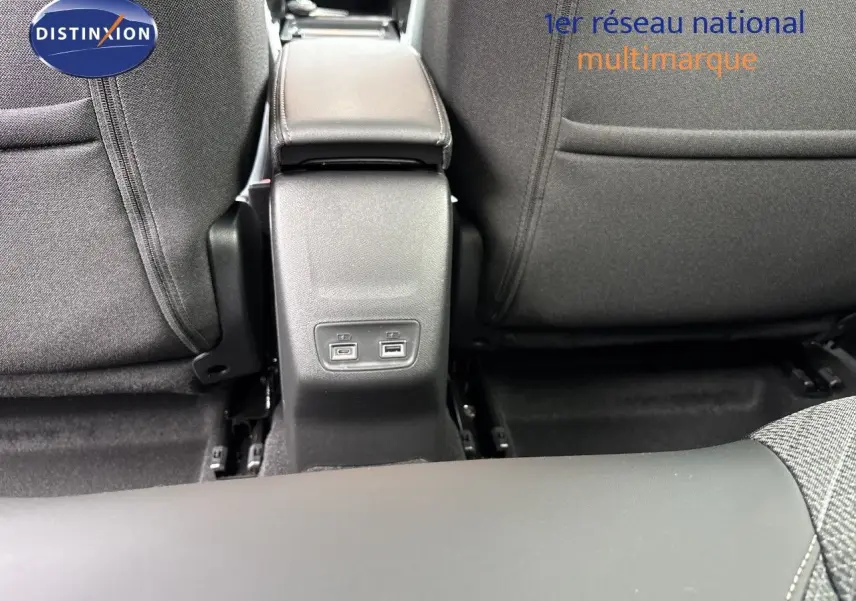 Vue rapprochée de la console centrale arrière avec ports USB, entre les sièges tissu gris d’une Peugeot 208 électrique 2026.