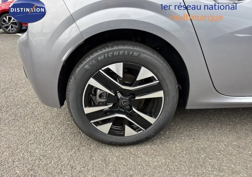 Gros plan sur la roue avant gauche de la Peugeot 208 électrique gris Artense métal avec jante alliage bicolore.